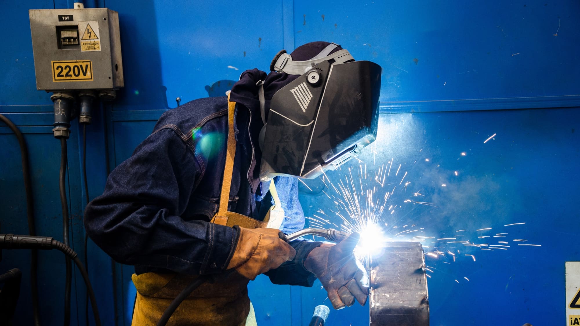 Welder in protective gear working at a job site at dusk