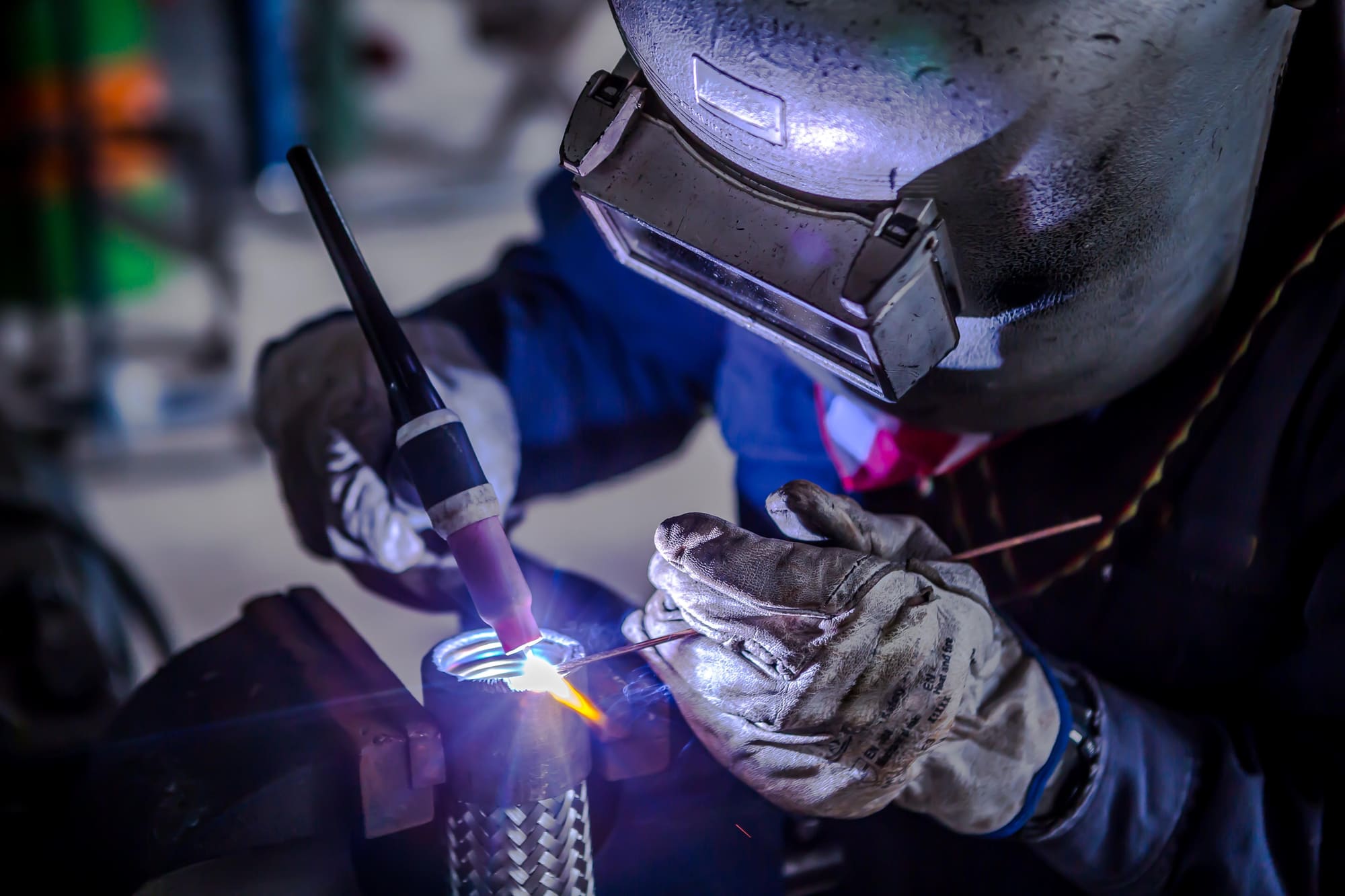 Welder using a torch on a pipe fitting in close detail